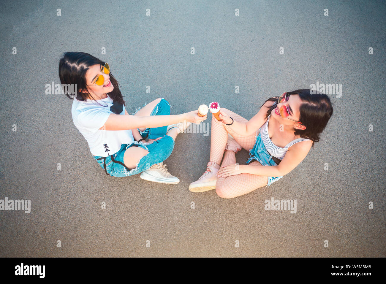 Zwei junge weibliche Freunde genießen Eis Stockfoto