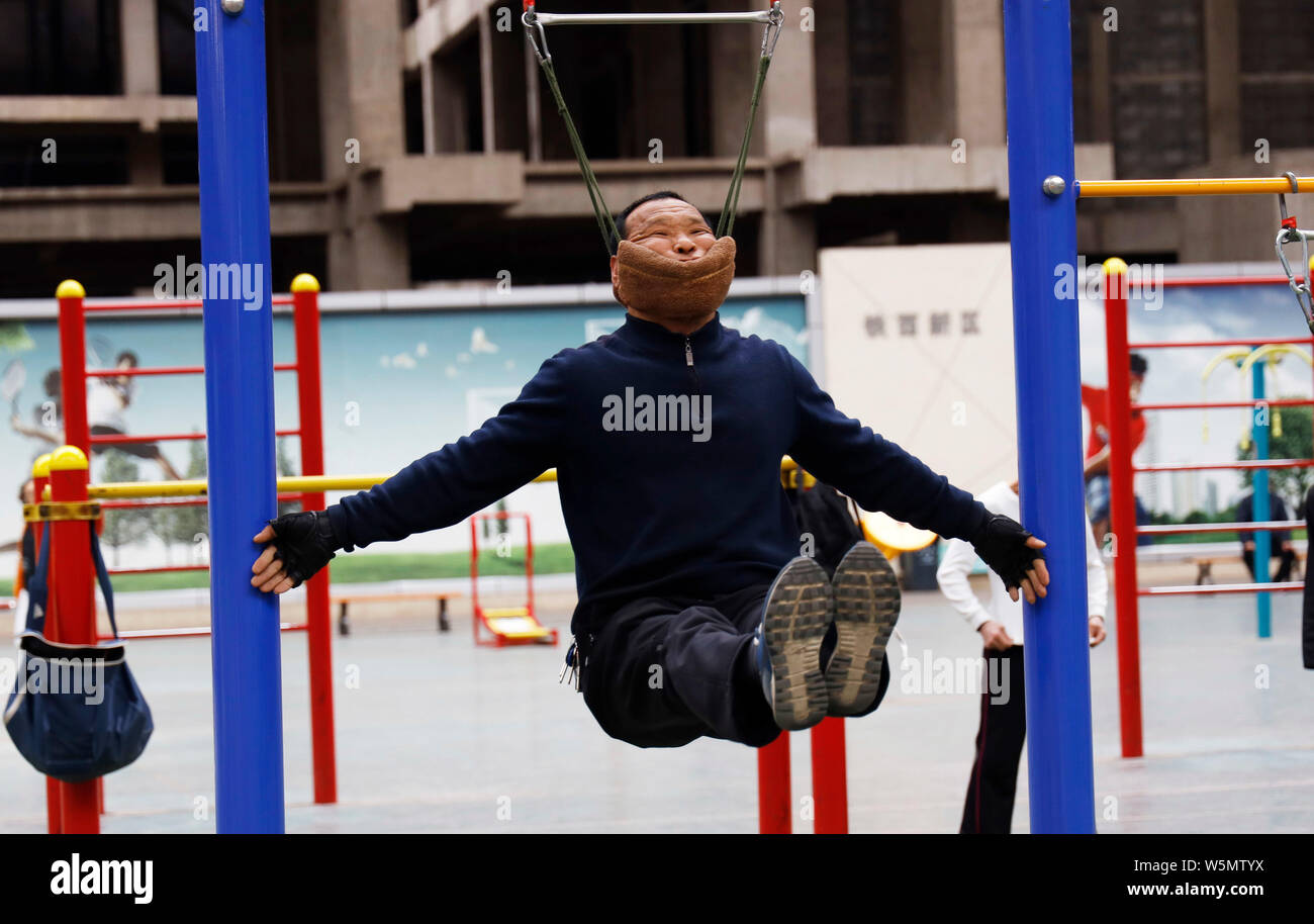 Der 57-jährige Chinese Sun Rongchun Übungen mit einem improvisierten zervikalen Zugeinrichtung zu einem hohen Bar bei einer Sportanlage in Shenyang City angeschlossen Stockfoto