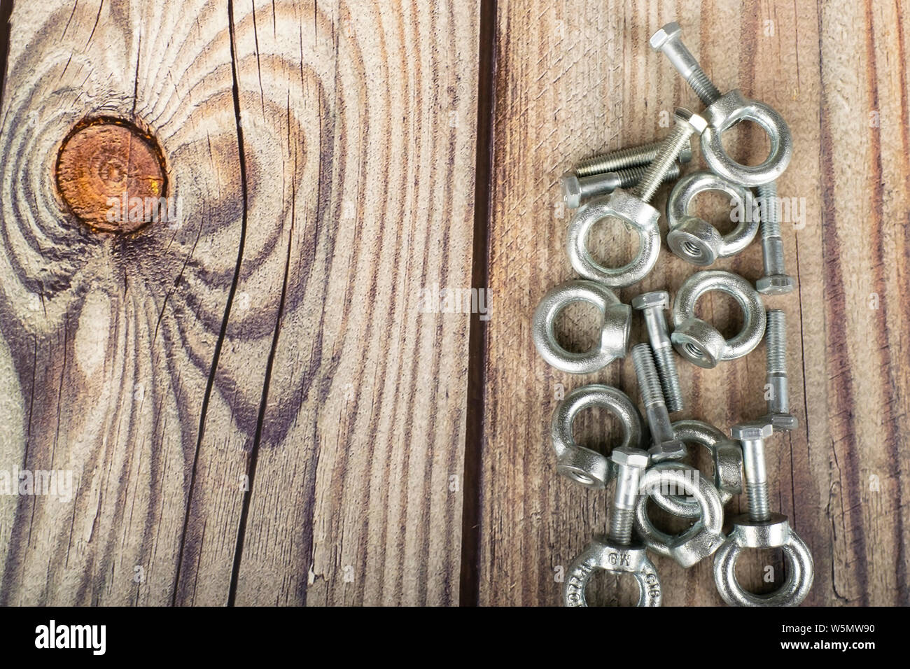Ringmuttern mit Schrauben, verzinkt auf Holz- Hintergrund. Stockfoto
