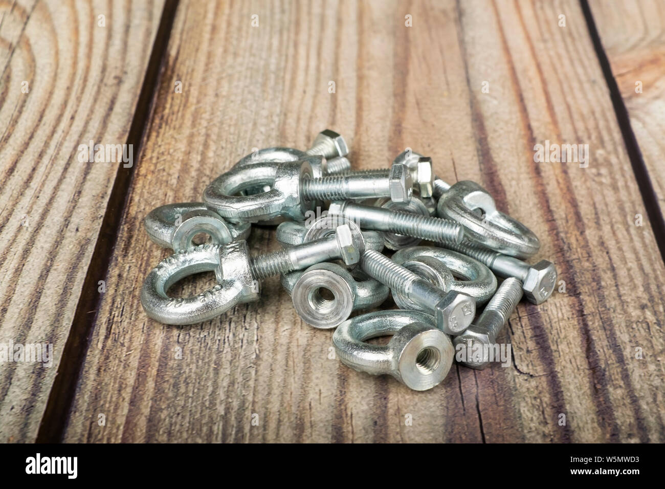 Ringmuttern mit Schrauben, verzinkt auf Holz- Hintergrund. Stockfoto