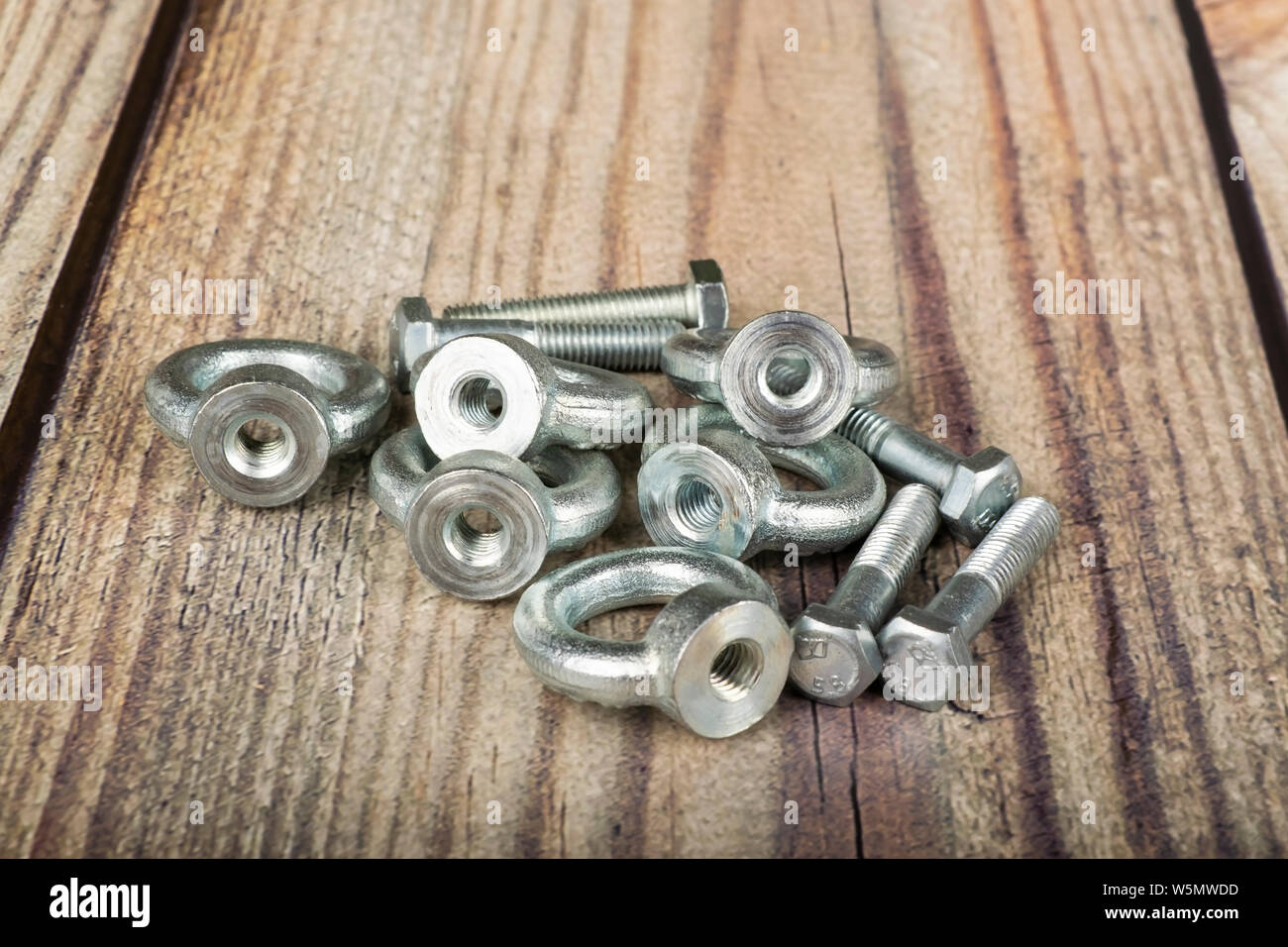Ringmuttern mit Schrauben, verzinkt auf Holz- Hintergrund. Stockfoto