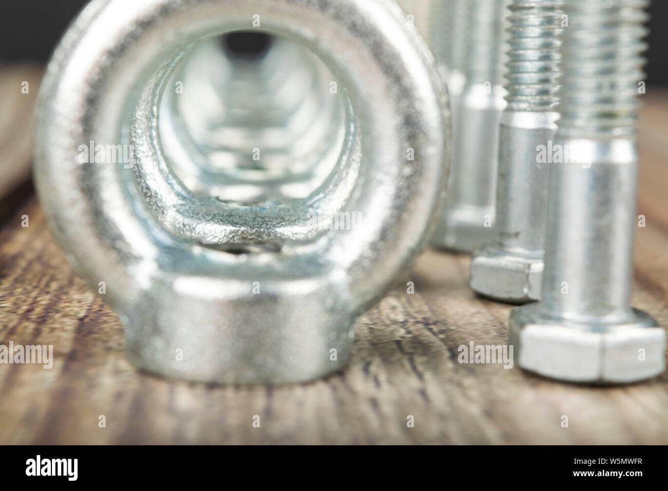 Ringmuttern mit Schrauben, verzinkt auf Holz- Hintergrund. Stockfoto