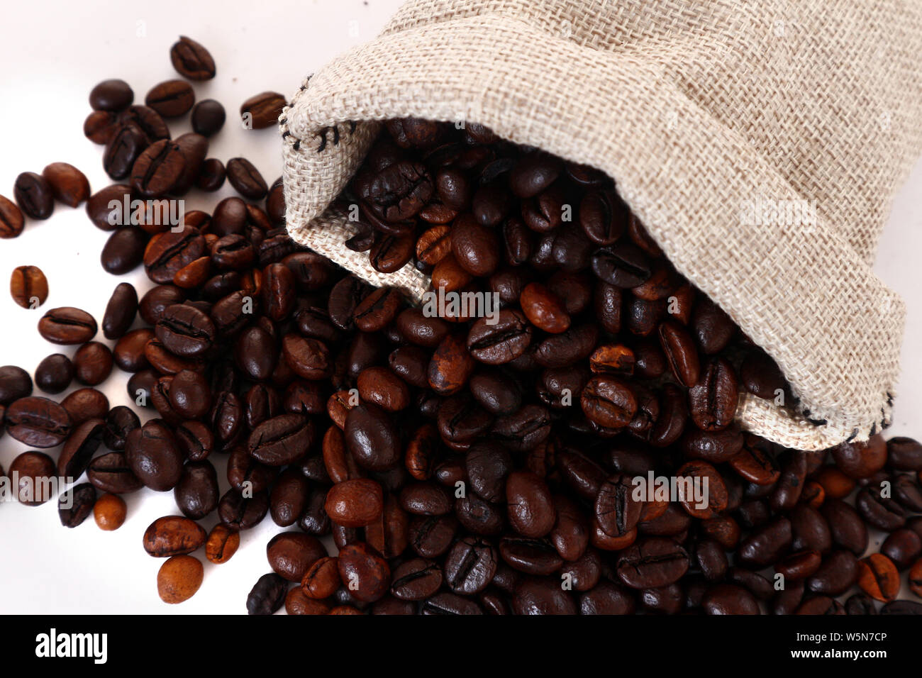 Foto von Kaffee Bohnen verschütten aus Jute Sack oder Beutel Schuß auf weißem Hintergrund Stockfoto