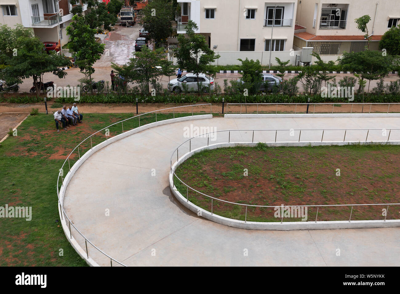 Gruppe von alten Männern auf einer Parkbank sitzt und spricht mit Blick auf einer Eisbahn in einem neu errichteten Wohngebiet gated community in Hyderabad, Indien. Stockfoto