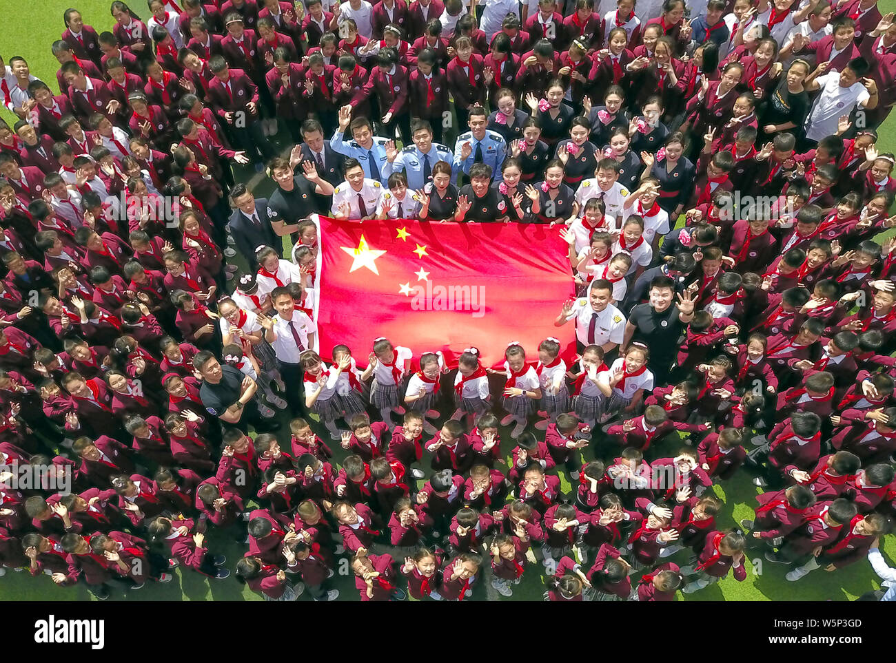 Grundschüler, Flugbegleiter und Piloten aus China Eastern Airlines sammeln eine nationale Flagge auf der Chinesischen Valentinstag in zu umkreisen. Stockfoto
