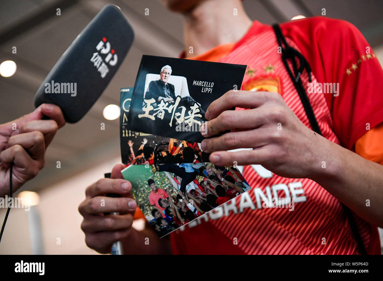 Chinesische Fans halten Banner Unterstützung von Marcello Lippi Zurück zur zweiten Stint als Cheftrainer der chinesischen Nationalmannschaft bei der guangzho zu zeigen Stockfoto