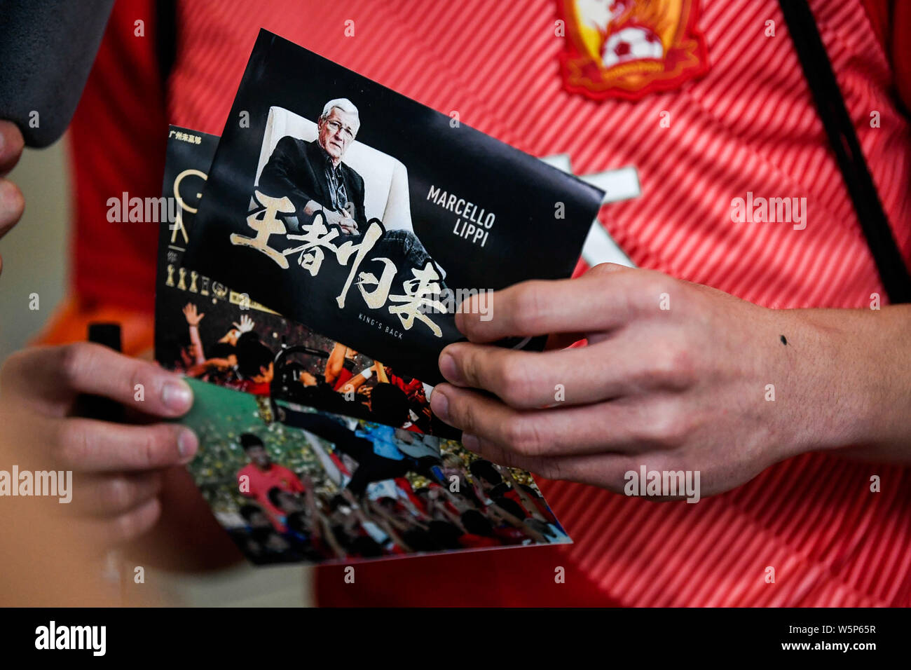 Chinesische Fans halten Banner Unterstützung von Marcello Lippi Zurück zur zweiten Stint als Cheftrainer der chinesischen Nationalmannschaft bei der guangzho zu zeigen Stockfoto