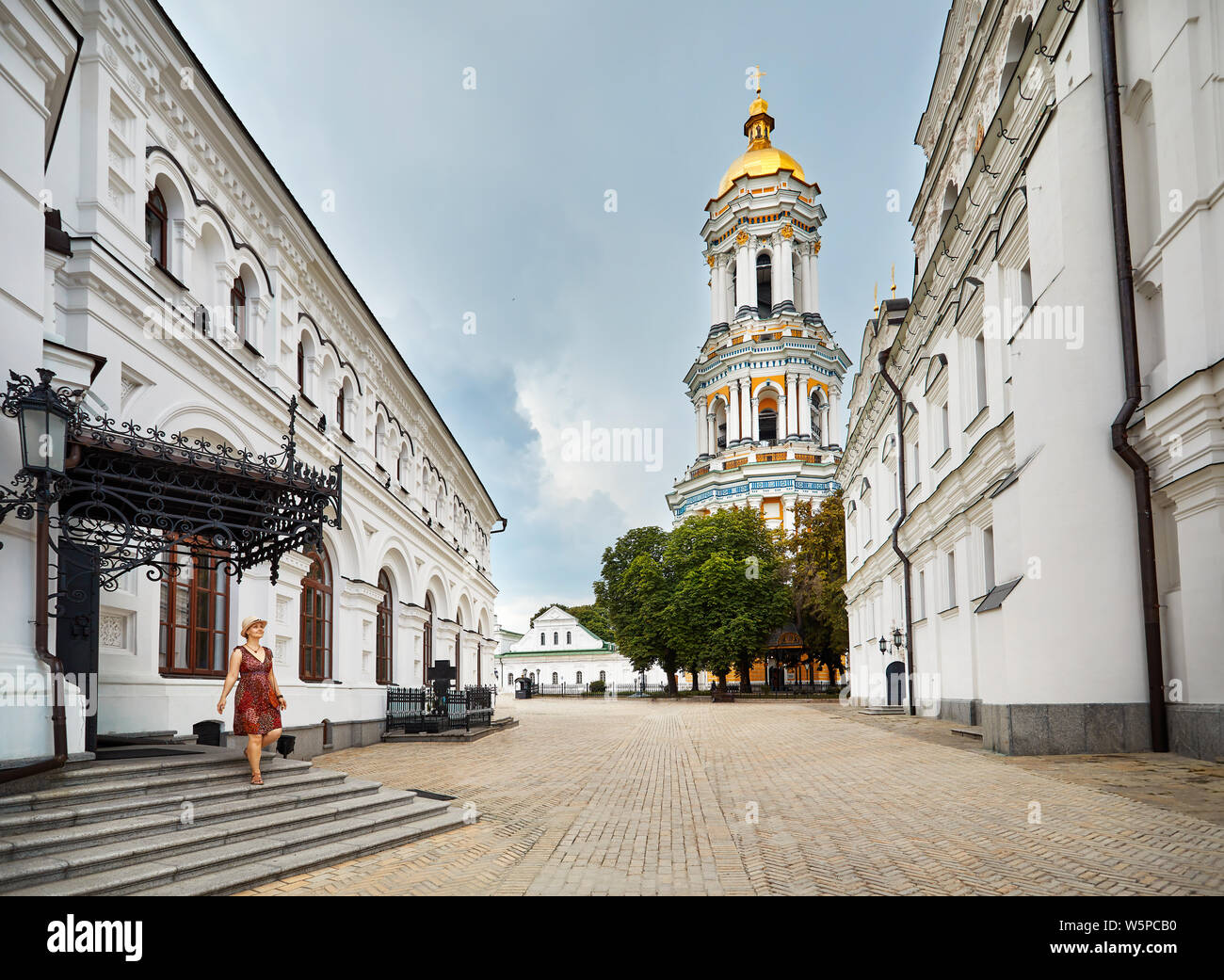 Junge touristische Frau wandern in der Nähe von Bell Tower mit goldenen Kuppel in Kiew Pechersk Lavra Christian komplex. Alte historische Architektur in Kiew, Ukraine Stockfoto