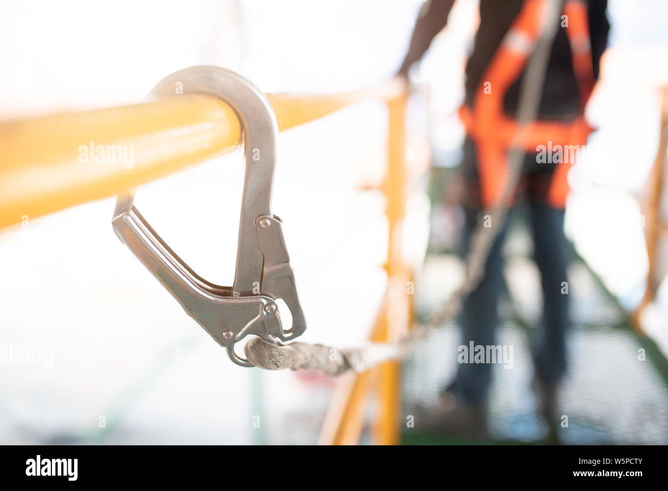 Industriearbeiter mit Sicherheitsschlaufe, die an der Stange hängen Stockfoto