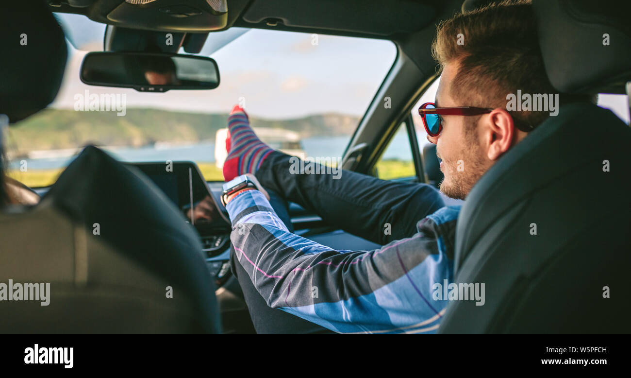 Junger Mann ruhen die Füße hoch sitzen auf dem Auto Stockfoto