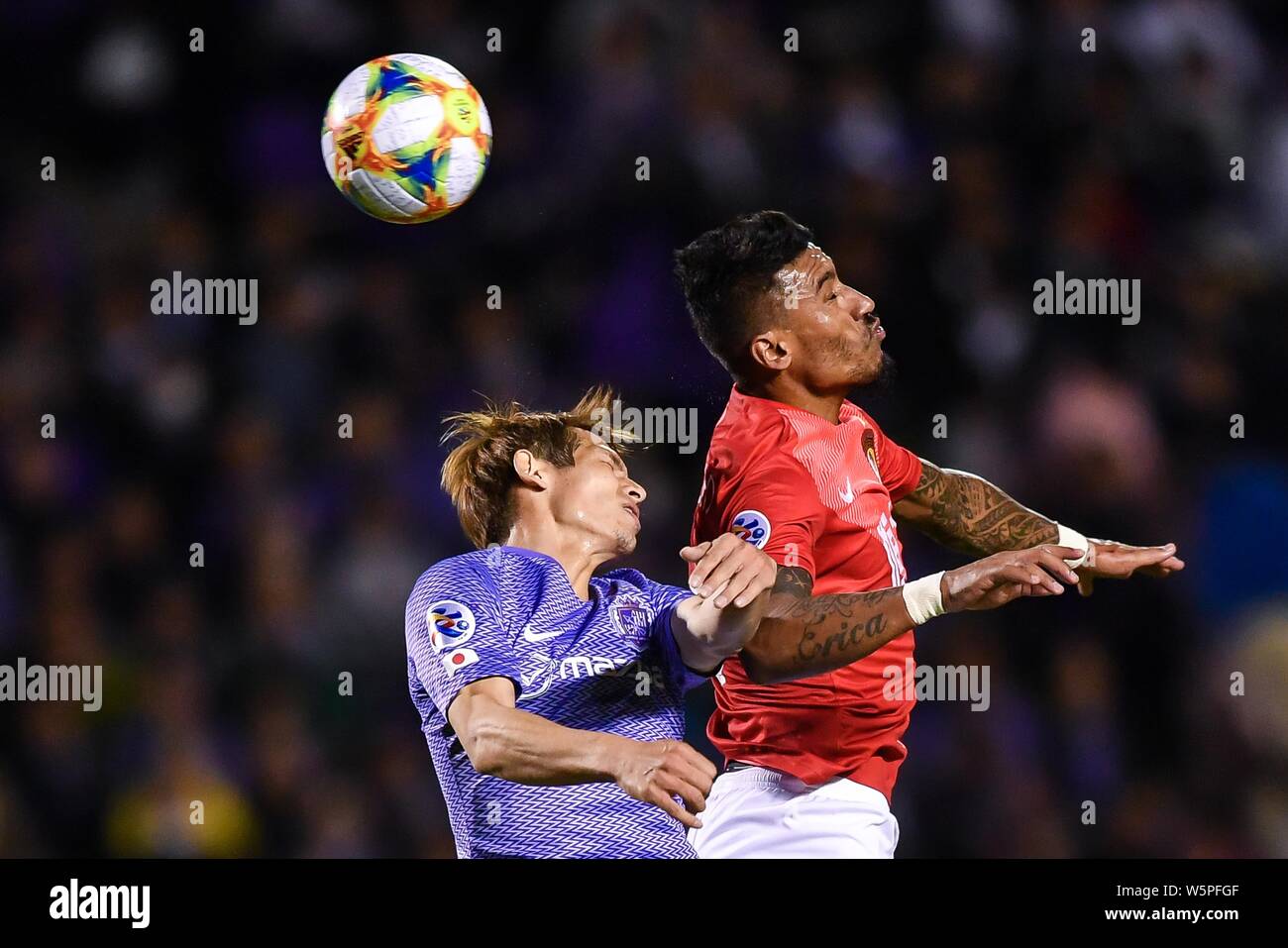 Brasilianische Fußballspieler Paulinho, top, der von China Guangzhou Evergrande Taobao F.C. leitet den Ball gegen einen Spieler von Japan Sanfrecce Hiroshima F. Stockfoto