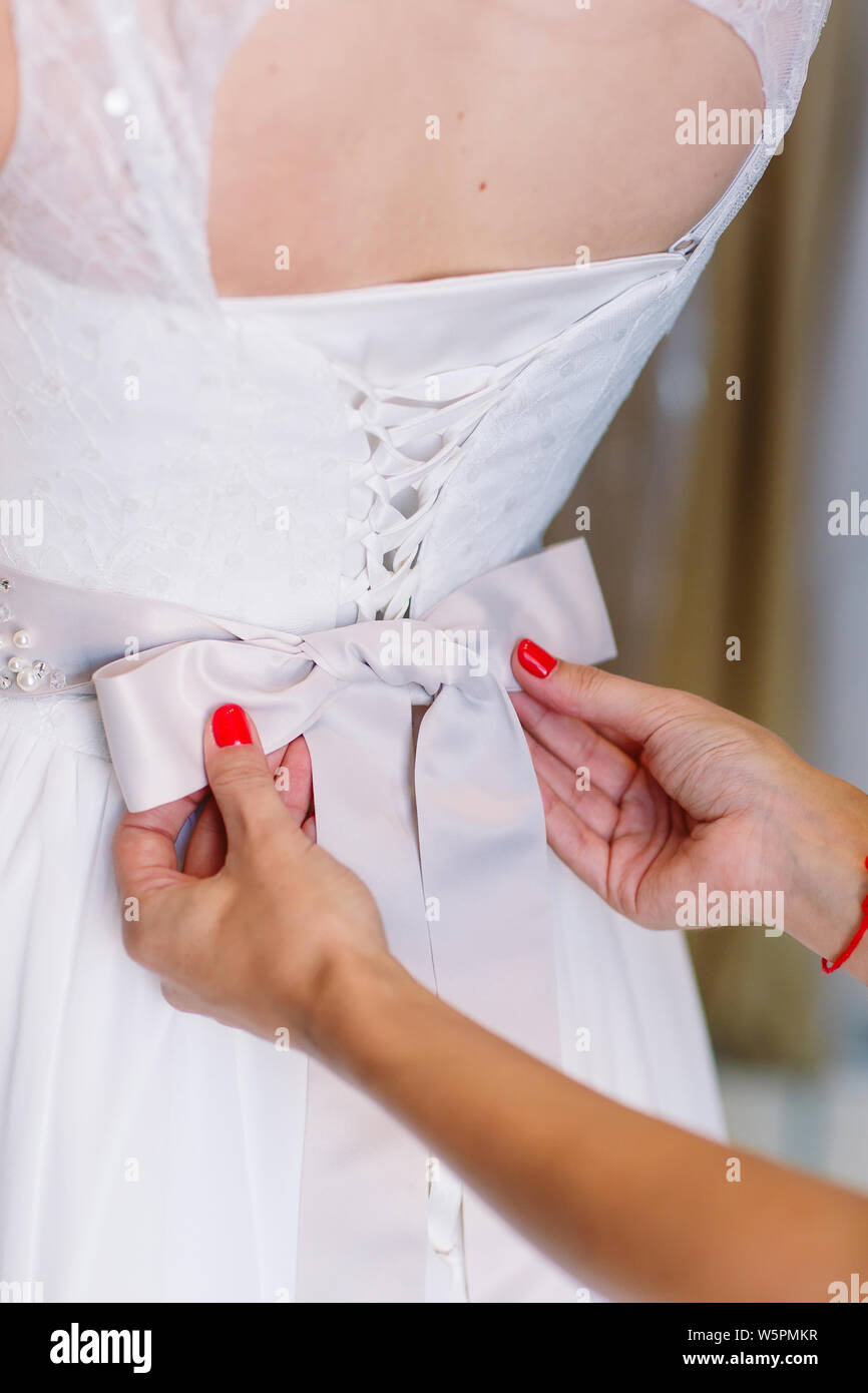 Frauen, die versuchen, auf Hochzeit Kleid in einem Shop mit Frauen assistant. Stockfoto
