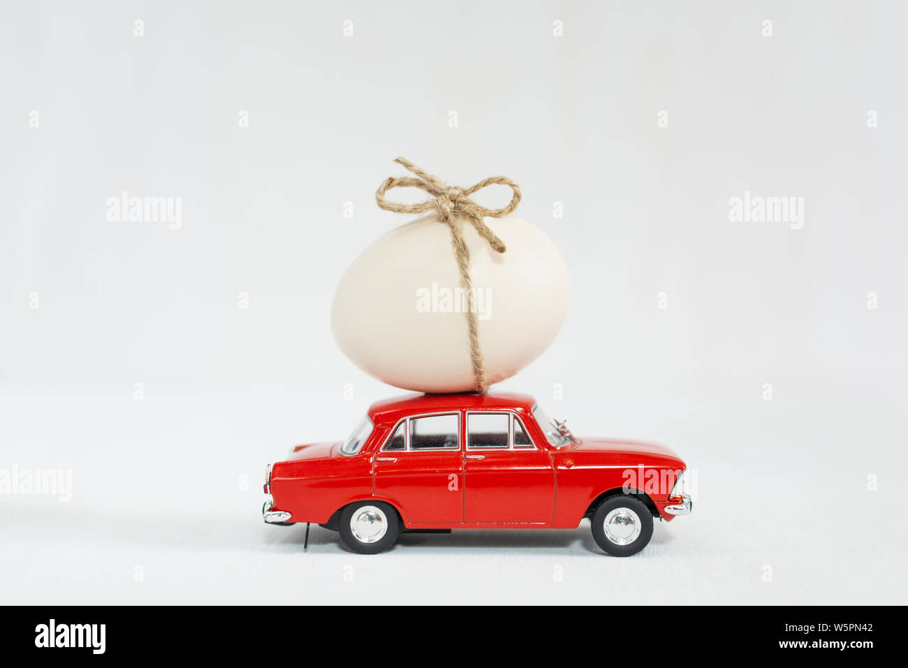 Red vintage Spielzeugauto mit Huhn Ei auf dem Dach. Isolierte Bild auf weißem Hintergrund. Stockfoto
