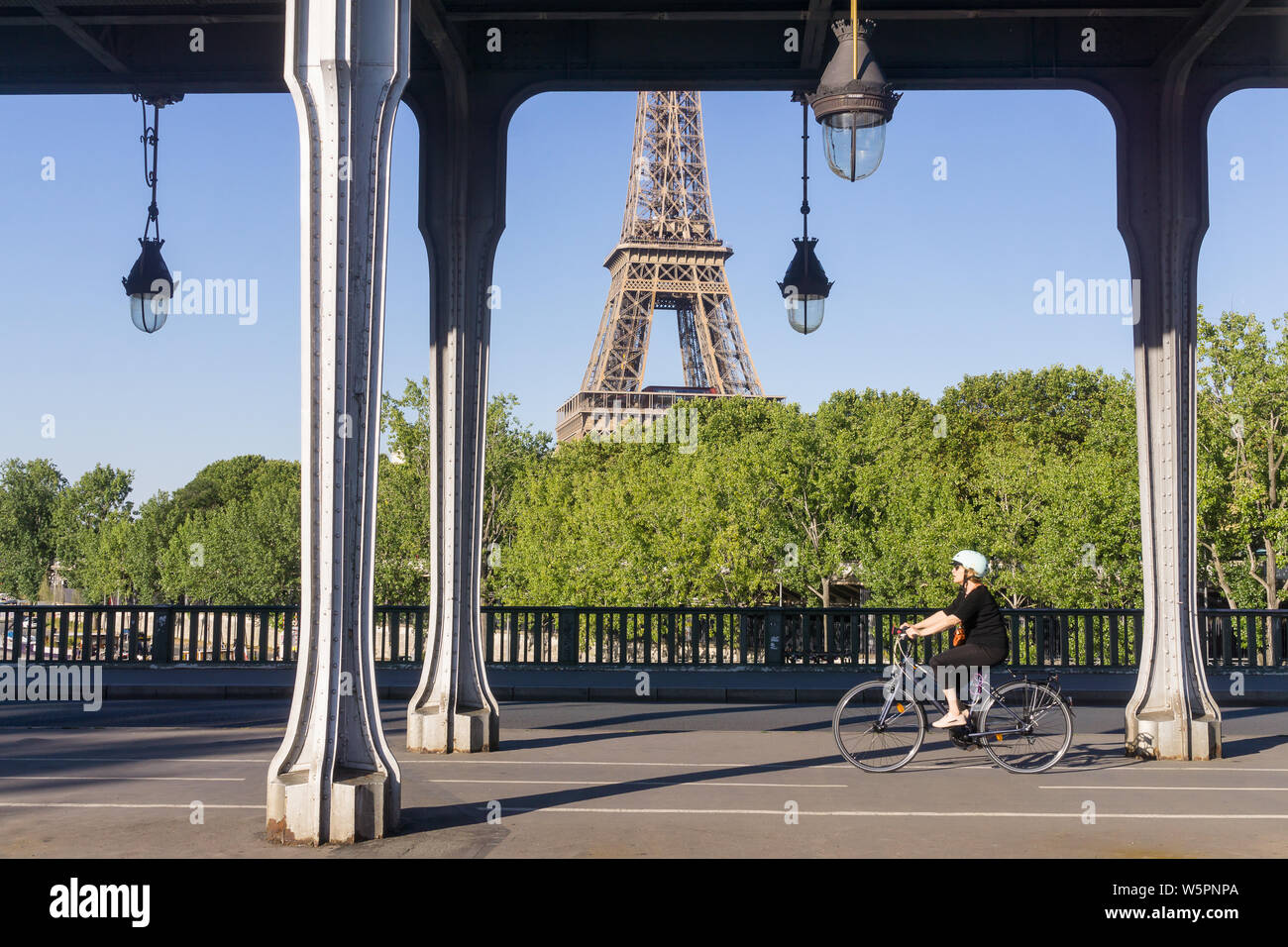 Paris mit dem Fahrrad - eine Frau tragen Helm Radfahren über die Bir Hakeim Brücke in Paris, Frankreich, Europa. Stockfoto