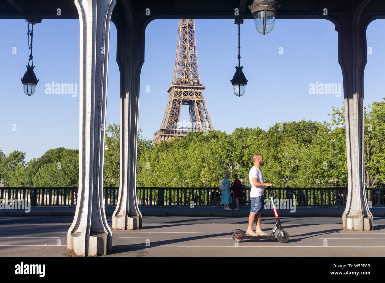 Paris Elektroroller - ein Mann auf einem Elektroroller reiten über die Bir Hakeim Brücke in Paris, Frankreich, Europa. Stockfoto