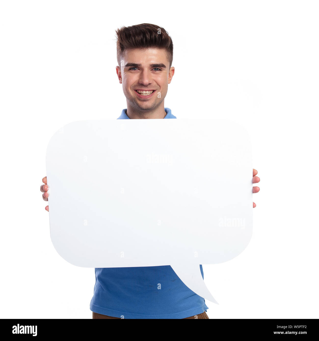 Glückliche junge legerer Mann hält ein blanck Sprechblase auf weißem Hintergrund Stockfoto