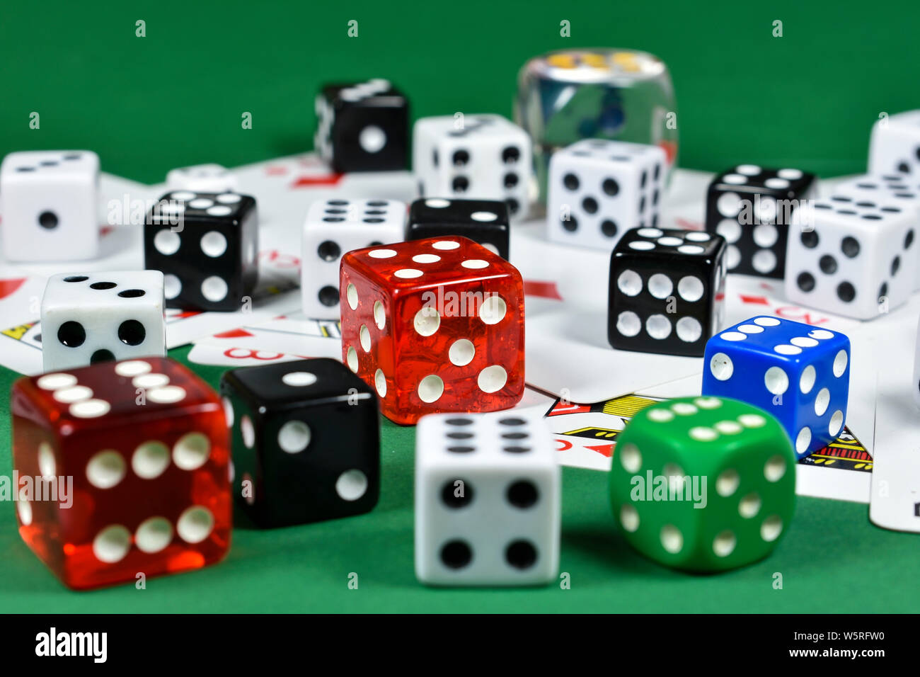 Close up konzeptuelle Bild mit einer Reihe von farbigen Würfel über mehrere Karten spielen, auf grüne Oberfläche Stockfoto