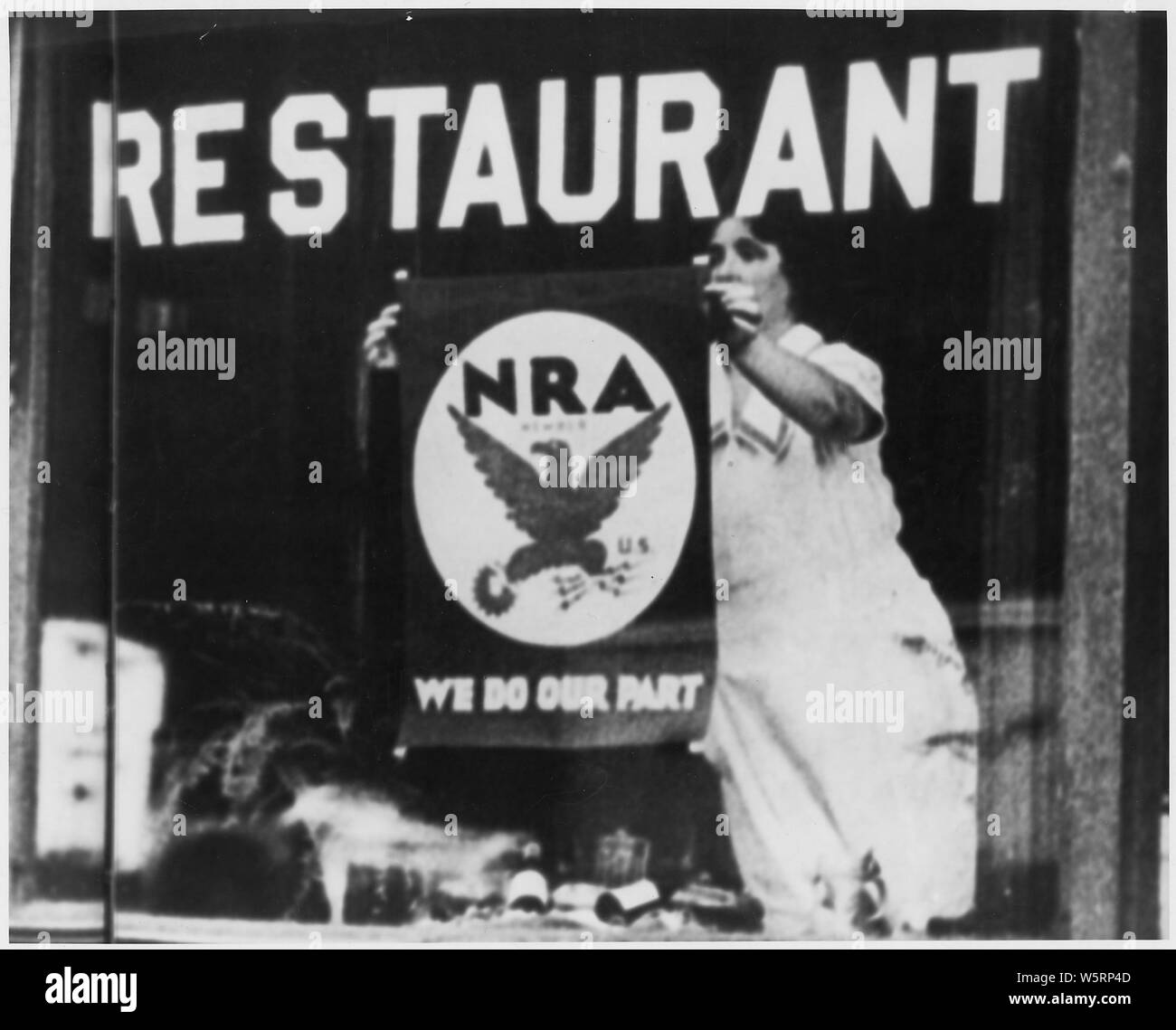 NRA: Blue Eagle Emblem: Poster im Restaurant Fenster angezeigt, aus dem ihre Teilnahme und die Unterstützung der Regierung Programm: Frau hängende Plakat im Fenster Stockfoto
