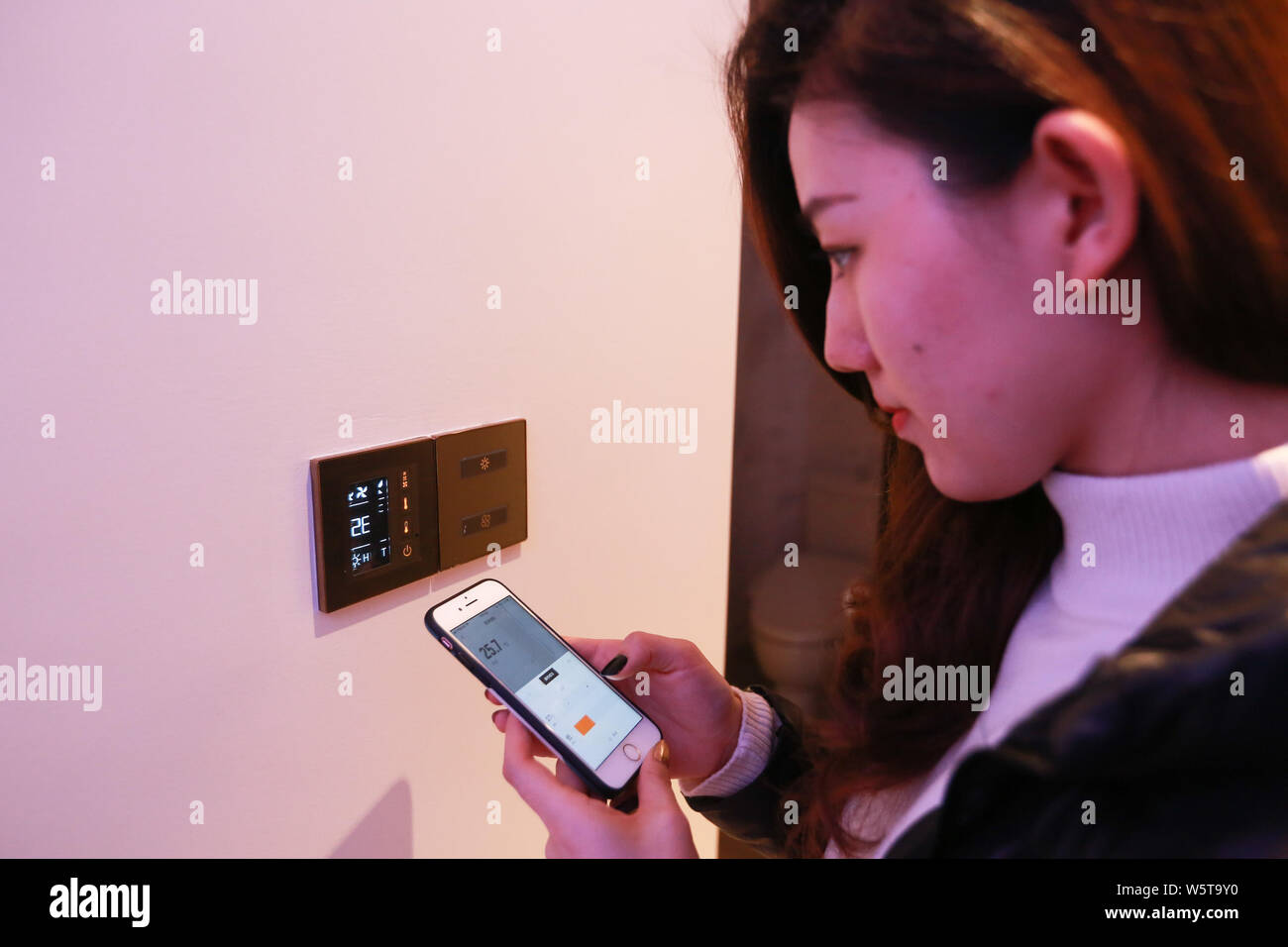 Ein chinesischer Gast nutzt das spezifische App auf Ihr Smartphone zu remote-control die Klimaanlage im Zimmer im futuristischen von Alibaba Hotel 'Flyzoo Ho Stockfoto