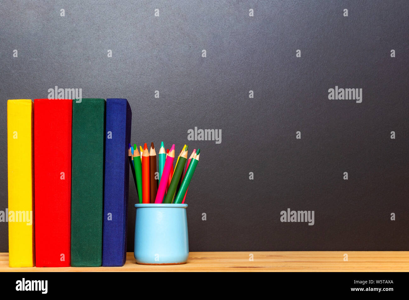 Gelb, Rot, Grün und Dunkelblau Bücher mit bunten Bleistifte vor der Tafel. Zurück zum Konzept der Schule. Bildung Hintergrund. Stockfoto