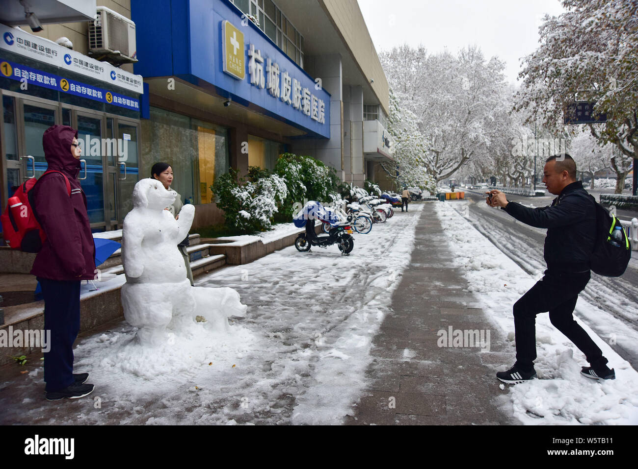 Passanten posieren für Fotos mit einem Schnee Skulptur mit der Form von Zhu Bajie, ein Charakter aus der Chinesischen Klassiker die Reise nach Westen, durch C Stockfoto