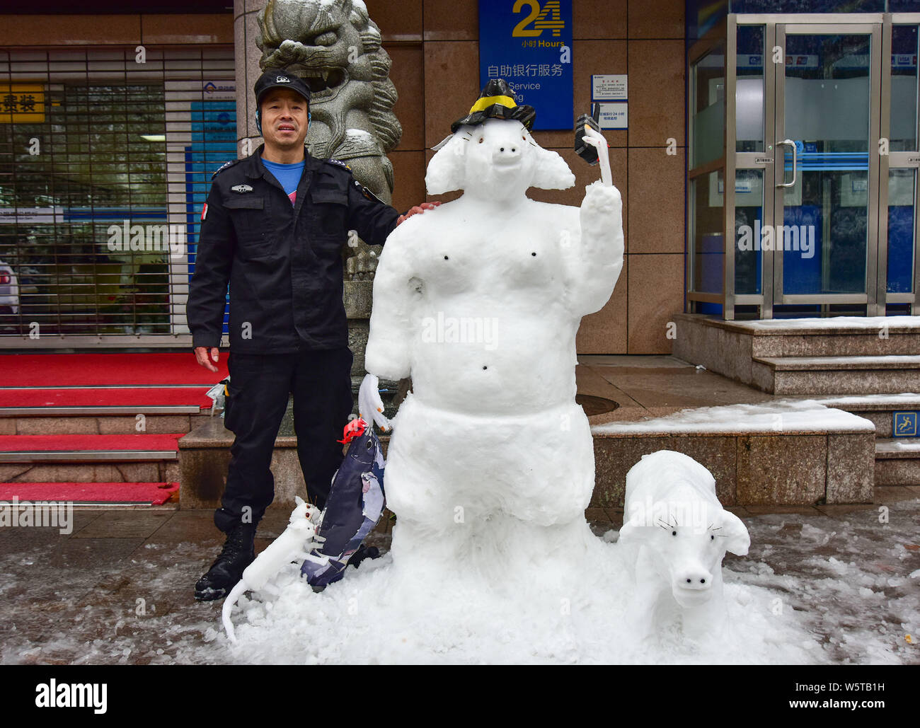 Chinesische bank Security Guard zunamen Du Posen für Fotos mit einem Schnee Skulptur mit der Form von Zhu Bajie, ein Charakter aus der Chinesischen Klassiker Stockfoto