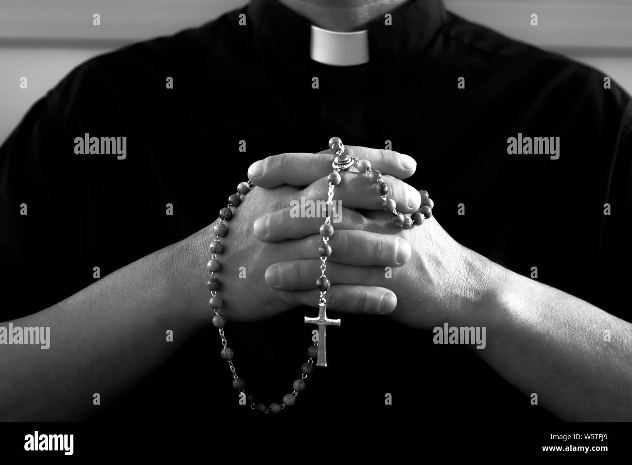 Priester mit Rosenkranz beten Stockfoto