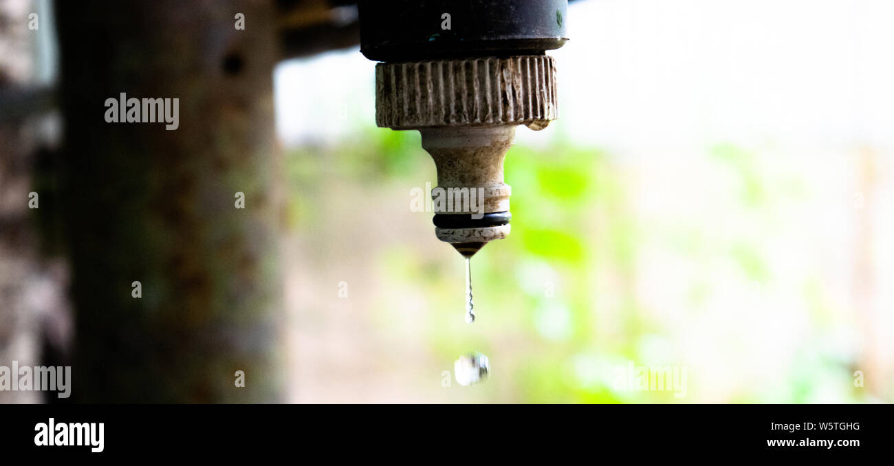Ein Wassertropfen fällt von einem schmutzigen und rostiges Wasser Leitungswasser engineering Thema Stockfoto