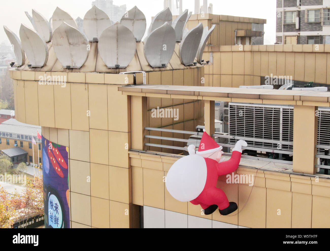 Ein Spielzeug ballon Santa Claus mit einem riesigen geschenkbeutel Klettert die Wand eines Kaufhauses in Nantong City, der ostchinesischen Provinz Jiangsu, 1. Dezem Stockfoto