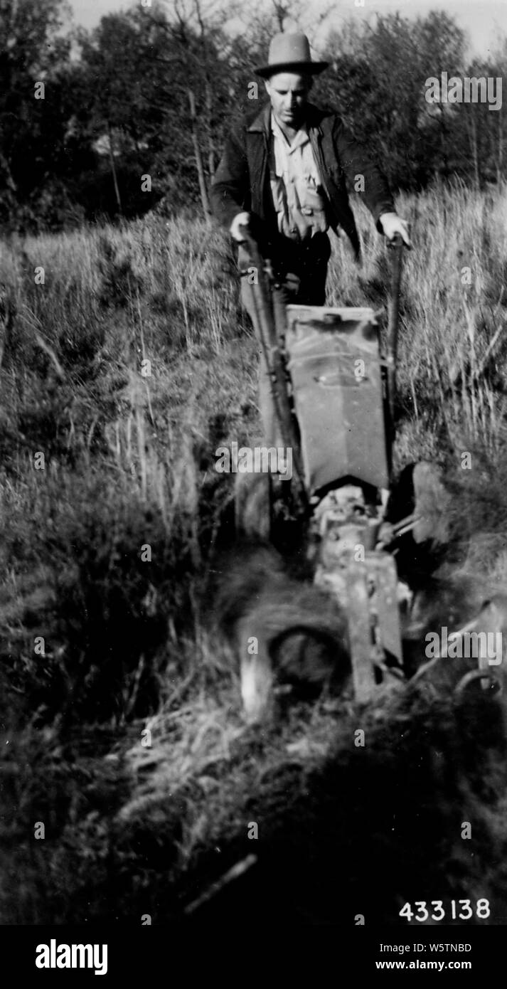 Foto von Ernst Traktor und Pflug Attachment; Umfang und Inhalt: Original Bildunterschrift: Schwer Traktor und Anbaugerät in Aktion Pflug in schweren Segge Gras gepflanzt, um shortleaf Pine. Stockfoto