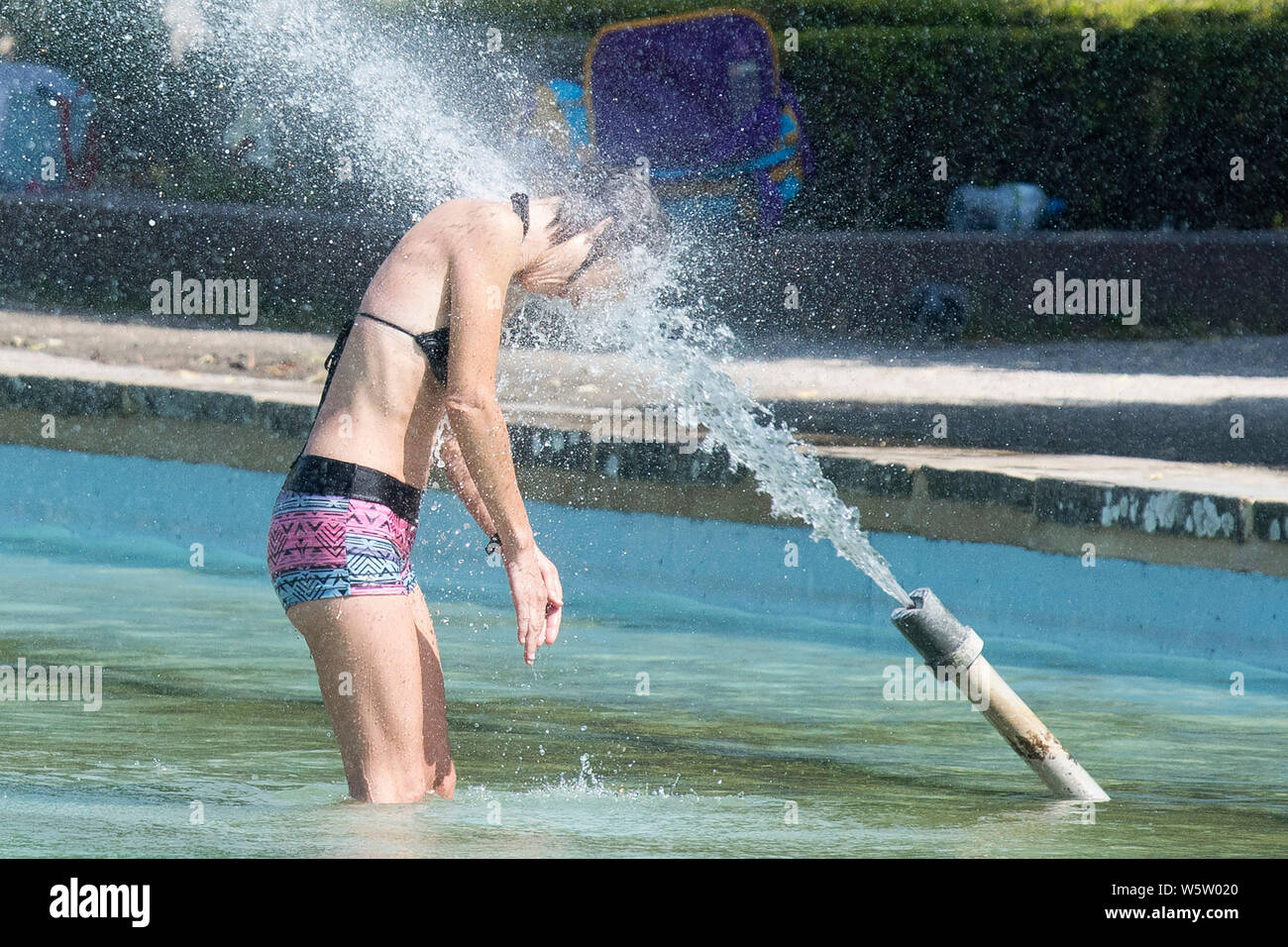 25.07.2019. Battersea, London, UK. Eine Frau, kühlt sich ab im Wasser Brunnen in Battersea Park als eine Hitzewelle fegt über Großbritannien. Stockfoto