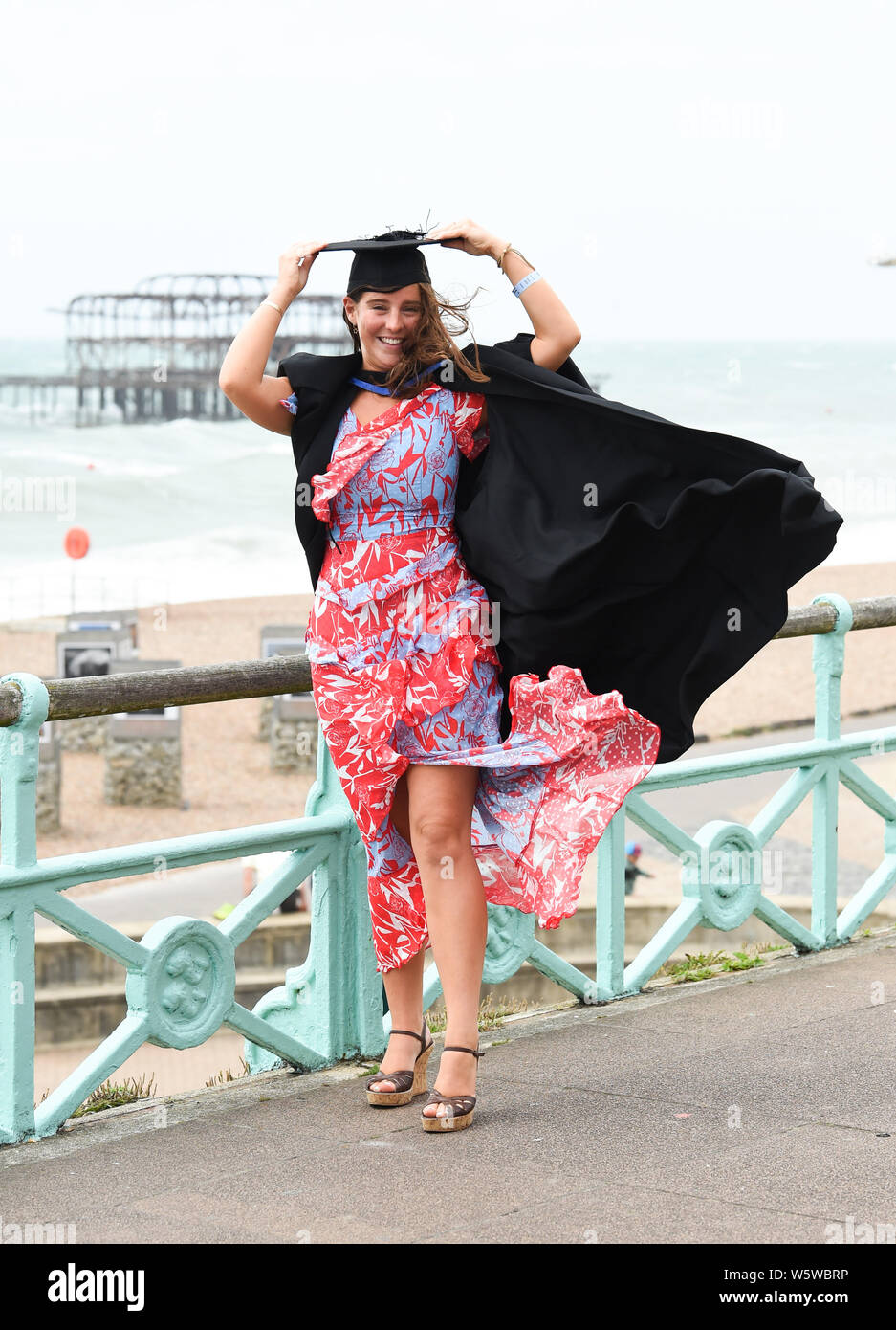 Brighton, UK. 30. Juli, 2019. Lois Grün hängt an ihr Mörtel Board nach dem Abschluss an der Universität Brighton an einem windigen Küste nach der Zeremonie. Foto: Simon Dack/Alamy leben Nachrichten Stockfoto
