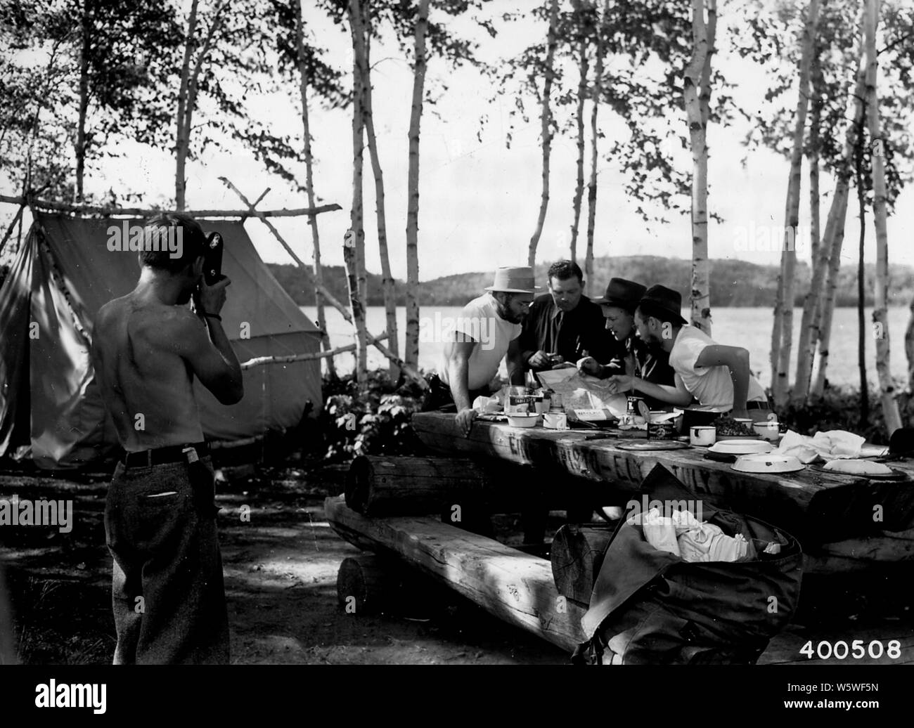 Foto von zwei Offiziere; Umfang und Inhalt: Original Bildunterschrift: Zwei Offiziere (Bill Trygg und Merle Moltrup) besuchen Sie drei Urlauber Camping in ein Kanu camp site auf Birke auf der South Arm des Messers See. Für eine bildliche Aufzeichnungen über ihre Reise eine der Camper ist ein Standbild aufnehmen des Waldes Officer. Stockfoto