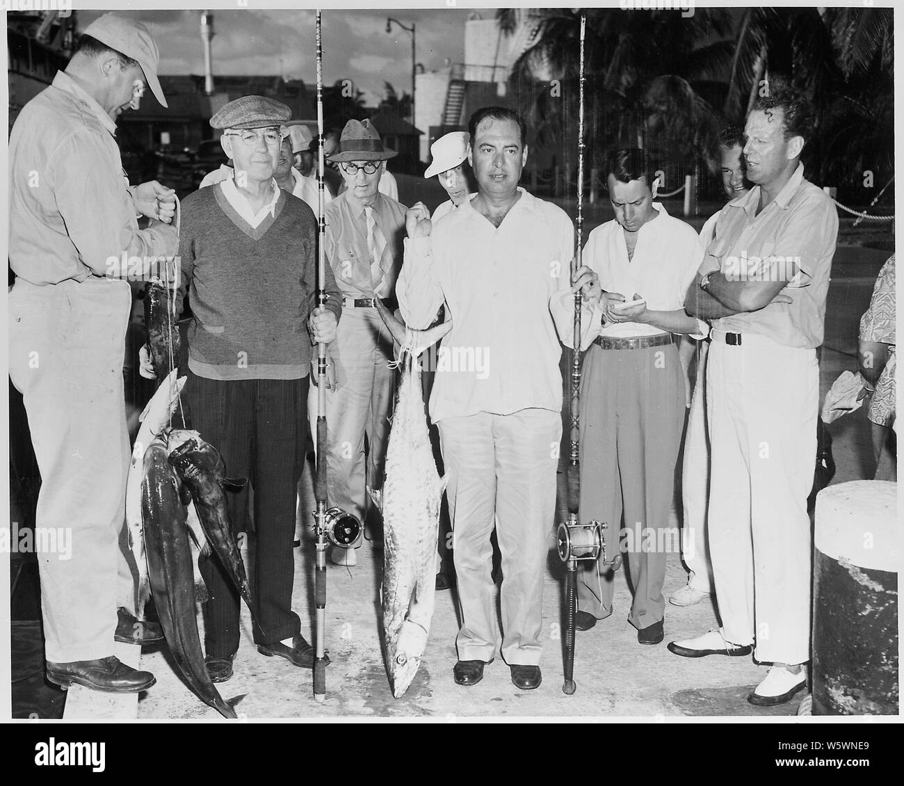 Foto des Naval Berater des Präsidenten, Kapitän Robert Dennison, posiert mit einem 29 Pfund König Makrele, die er auf einem fischenexpedition gefangen, während (nach rechts) Allgemeine Harry Vaughan, Korrespondenz William Hassett, Admiral William Leahy, Links und (ganz rechts) Special Counsel Clark Clifford Blick auf, während Präsident Trumans Urlaub in Key West, Florida. Stockfoto