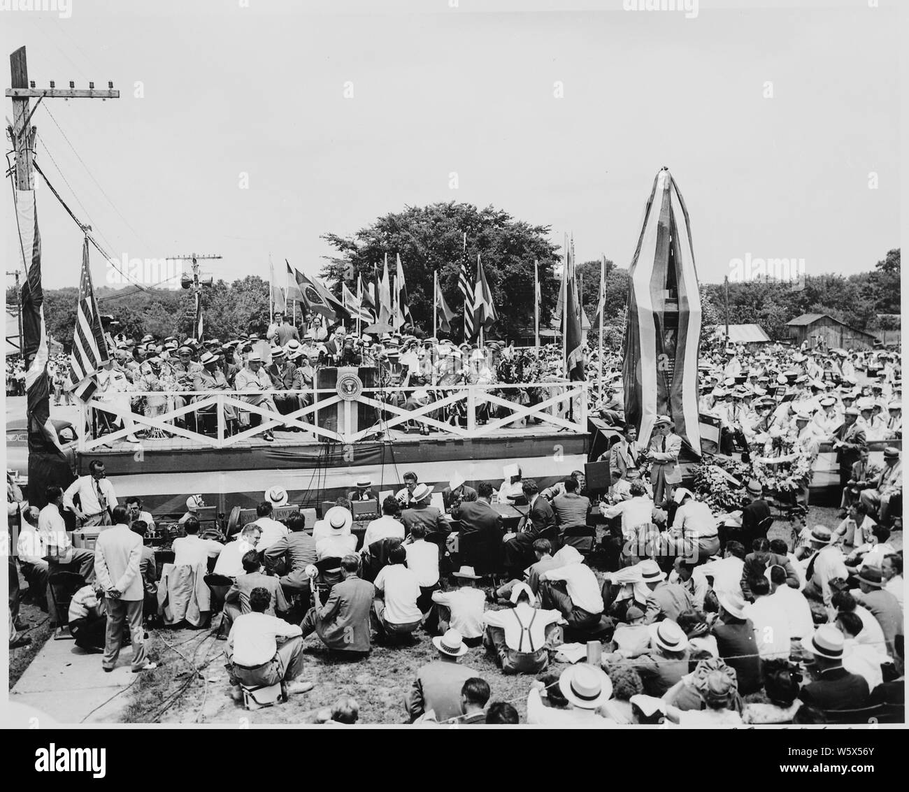 Präsident Harry S. Truman, Präsident Romulo Gallegos von Venezuela, und andere Würdenträger auf der Überprüfung der Plattform bei Bolivar, Missouri. Eine Masse ist um die Plattform versammelt, und drapierte Statue von Simon Bolivar ist auf der rechten Seite. Präsident Truman die Statue gewidmet. Ein unbekannter Mann spricht. Stockfoto