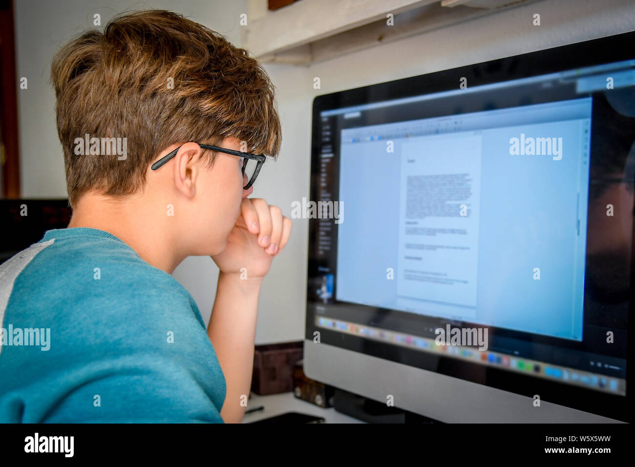 Schöne jugendlich Hausaufgaben mit dem Computer. Teenager online Arbeiten verbunden mit seinem Schulfreund. Technologie ermöglicht mit Fernbedienung frien zu kommunizieren Stockfoto