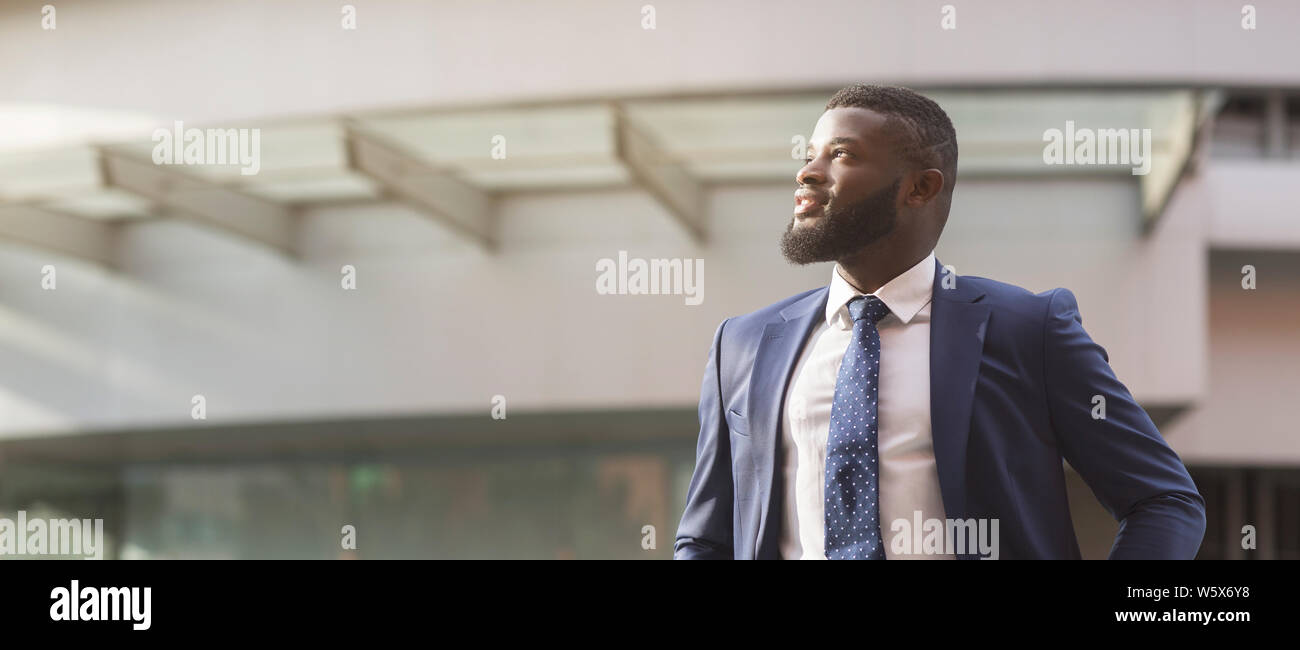 Afrikanischen Geschäftsmann weg schauen stehen vor dem Bürogebäude Stockfoto