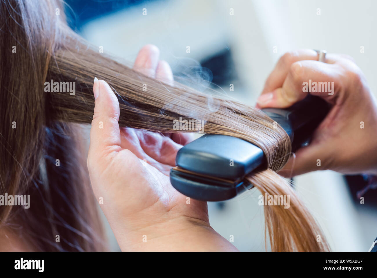 Friseur mit Bügeleisen auf das Haar der Frau Kunde Stockfoto