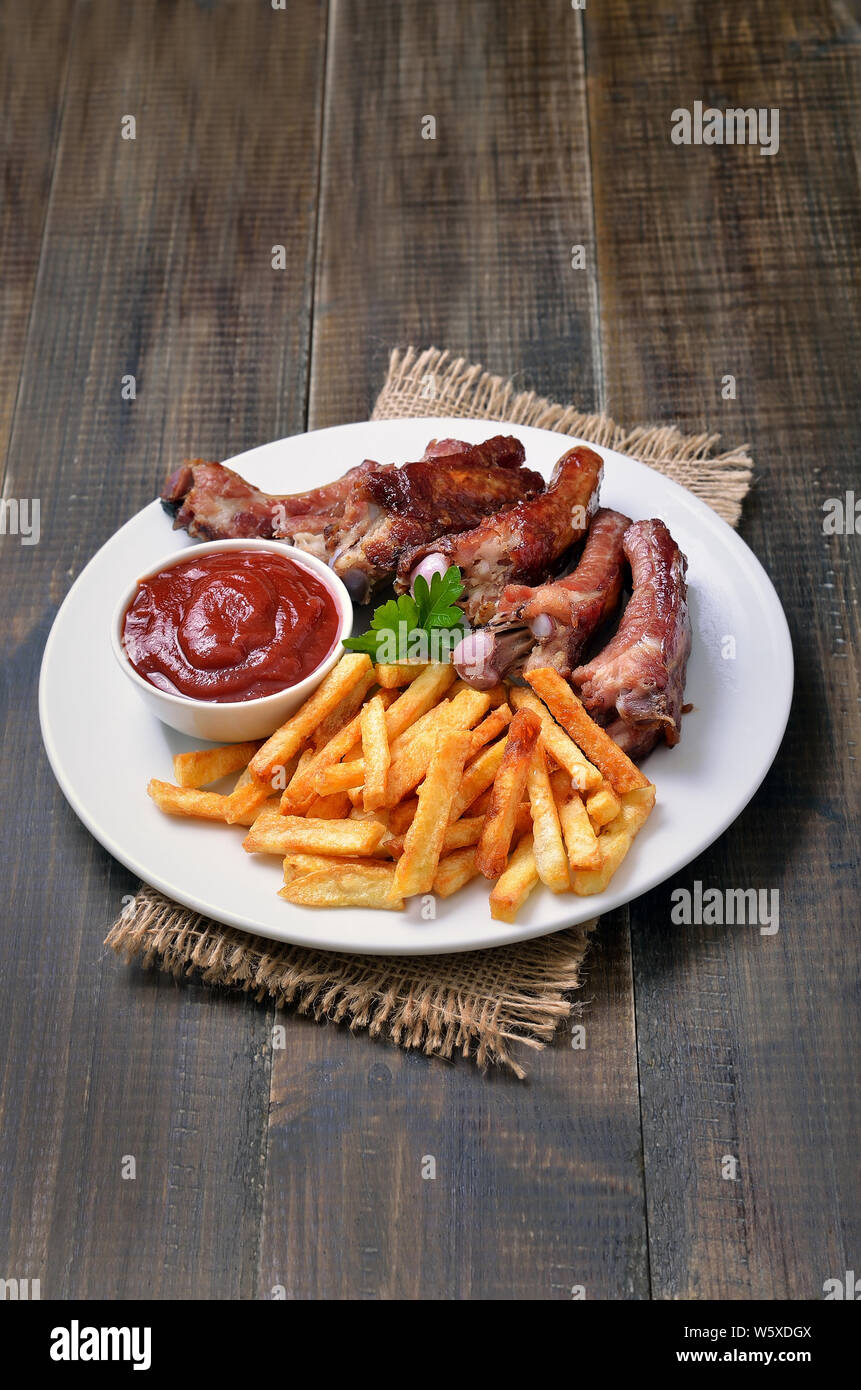 Pommes frites Kartoffeln, Rippchen und Tomatensauce auf weiße Platte Stockfoto