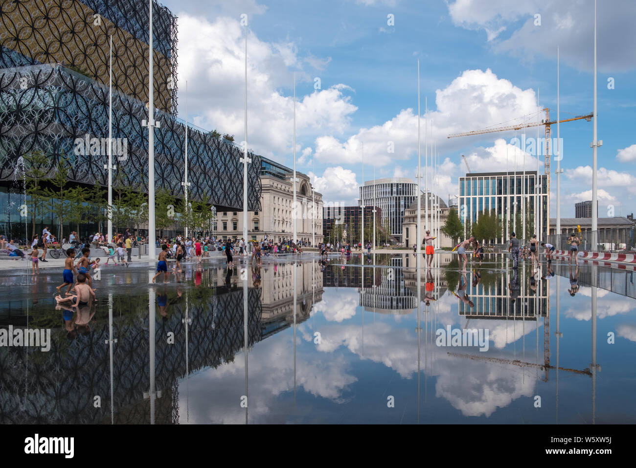 Kinder spielen und Abkühlen in den neuen Wasserspiel Spiegel und Brunnen in Centenary Square, Birmingham an einem heißen Tag Stockfoto