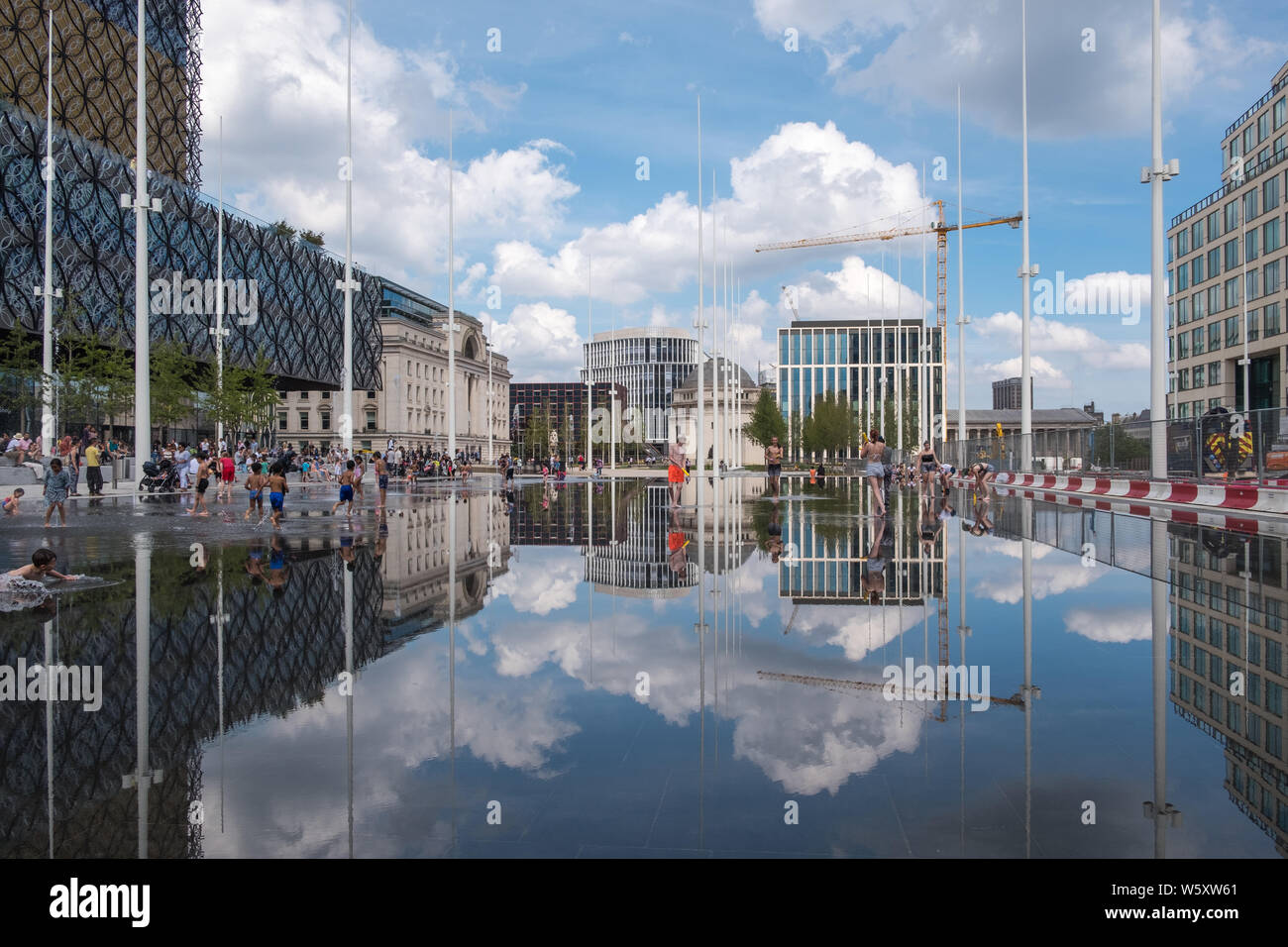 Kinder spielen und Abkühlen in den neuen Wasserspiel Spiegel und Brunnen in Centenary Square, Birmingham an einem heißen Tag Stockfoto