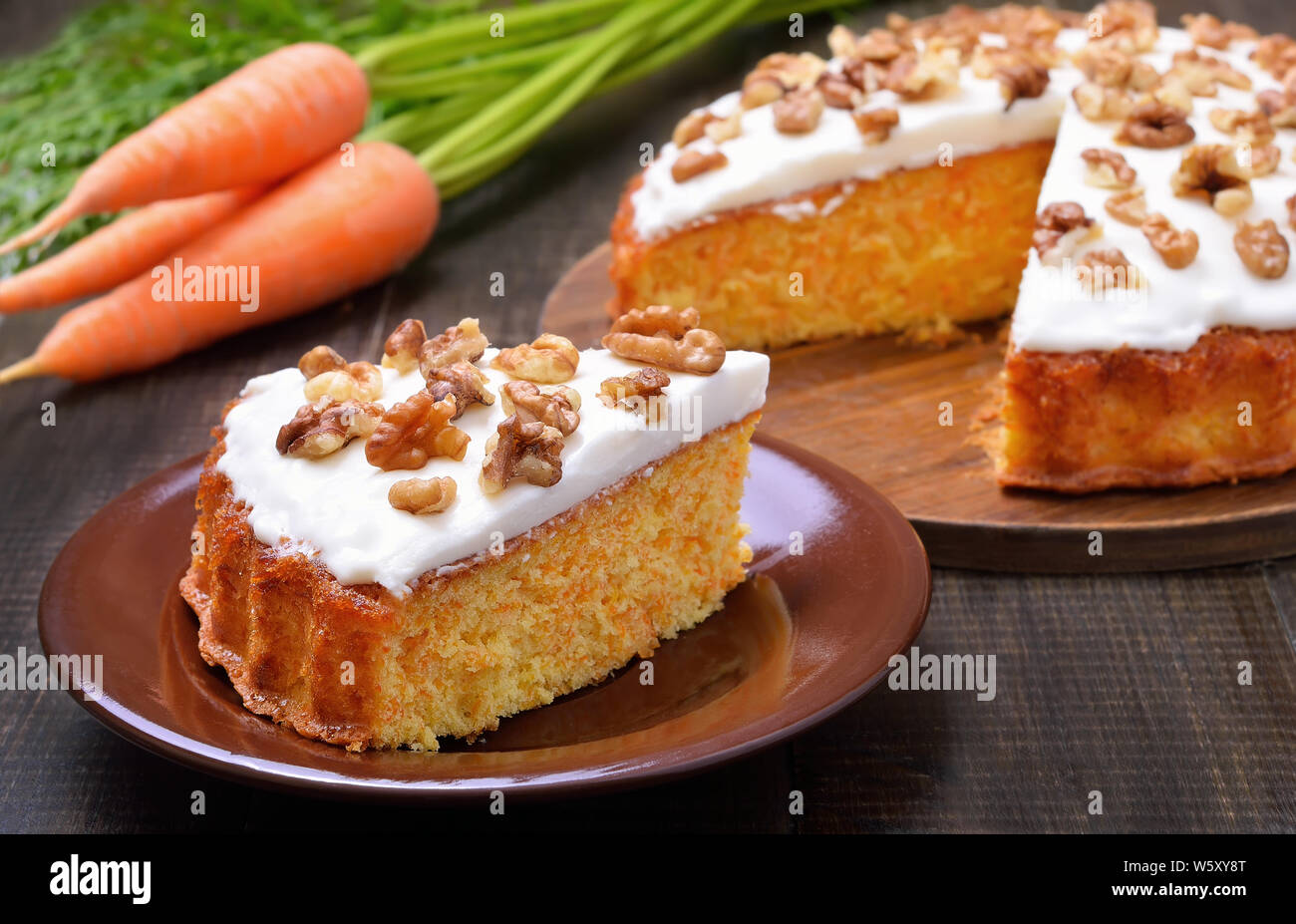 Stück Karottenkuchen mit Zuckerglasur dekoriert Walnuss auf hölzernen Tisch Stockfoto
