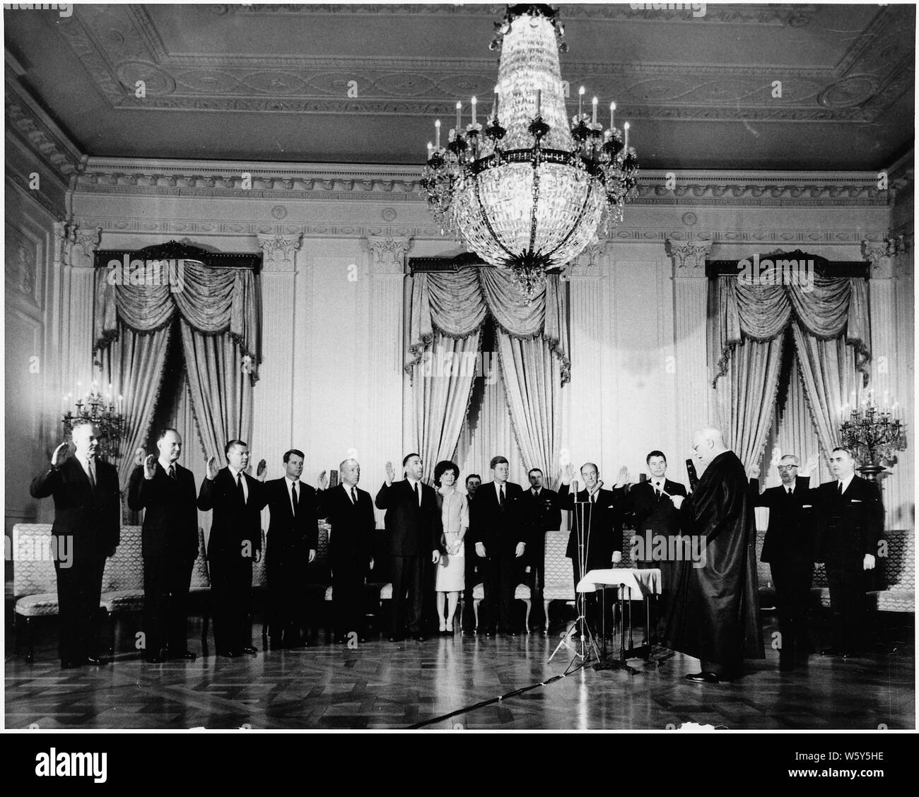 Swearing-In Zeremonie von Präsident Kennedy's Cabinet; Umfang und Inhalt: Swearing-In Zeremonie des Kabinetts von Präsident Kennedy. Chief Justice Earl Warren verwaltet Eid (L-R) Dean Rusk, Sec. Zustand, Douglas Dillon, Sec. Treasury, Robert S. McNamara, Sec. Verteidigung, Robert F. Kennedy, Attorney General, J., Postmaster General, Stewart Udall, Sec. Interieur, Frau Kennedy, Präsident Kennedy, Adlai E. Stevenson, Vertreter der UNO, Orville Freeman, Sec. Landwirtschaft (versteckt: Luther Hodges, Sec. Commerce) Arthur Goldberg, Sec. Arbeit, Abraham Ribicoff, Sec. Gesundheit, Bildung & Welfar Stockfoto