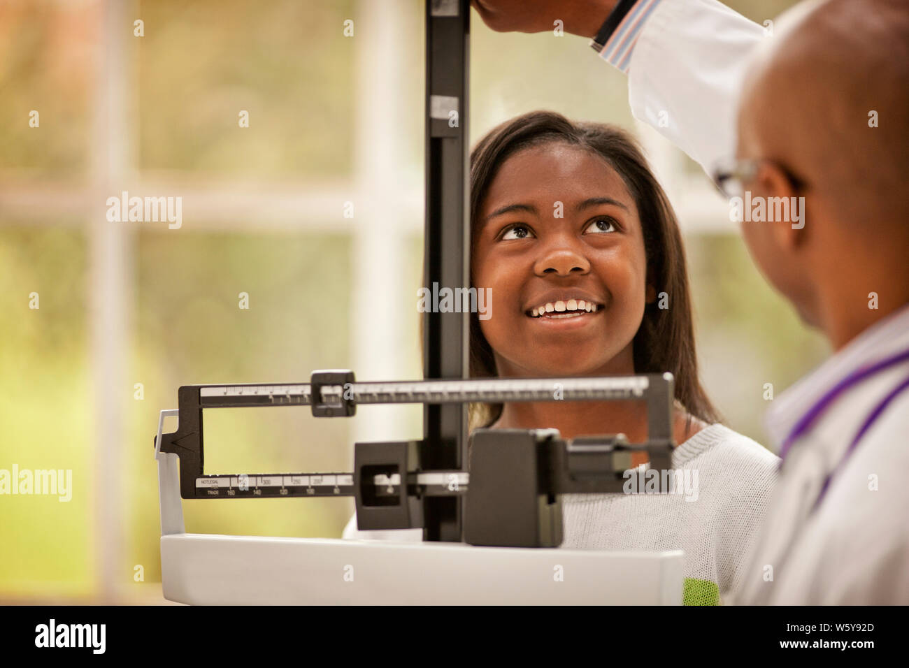 Smiling teenage Mädchen ihre Höhe von einem männlichen Arzt gemessen haben. Stockfoto