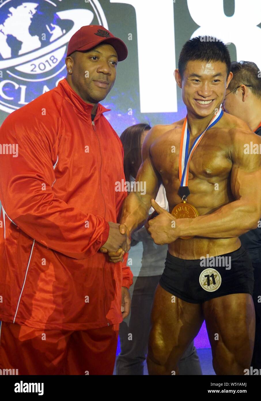 Jamaican-American IFBB professional Bodybuilder Shawn Rhoden, Links, Posen für Fotos mit einem Teilnehmer während einer Bodybuilding Wettkampf in Shanghai. Stockfoto