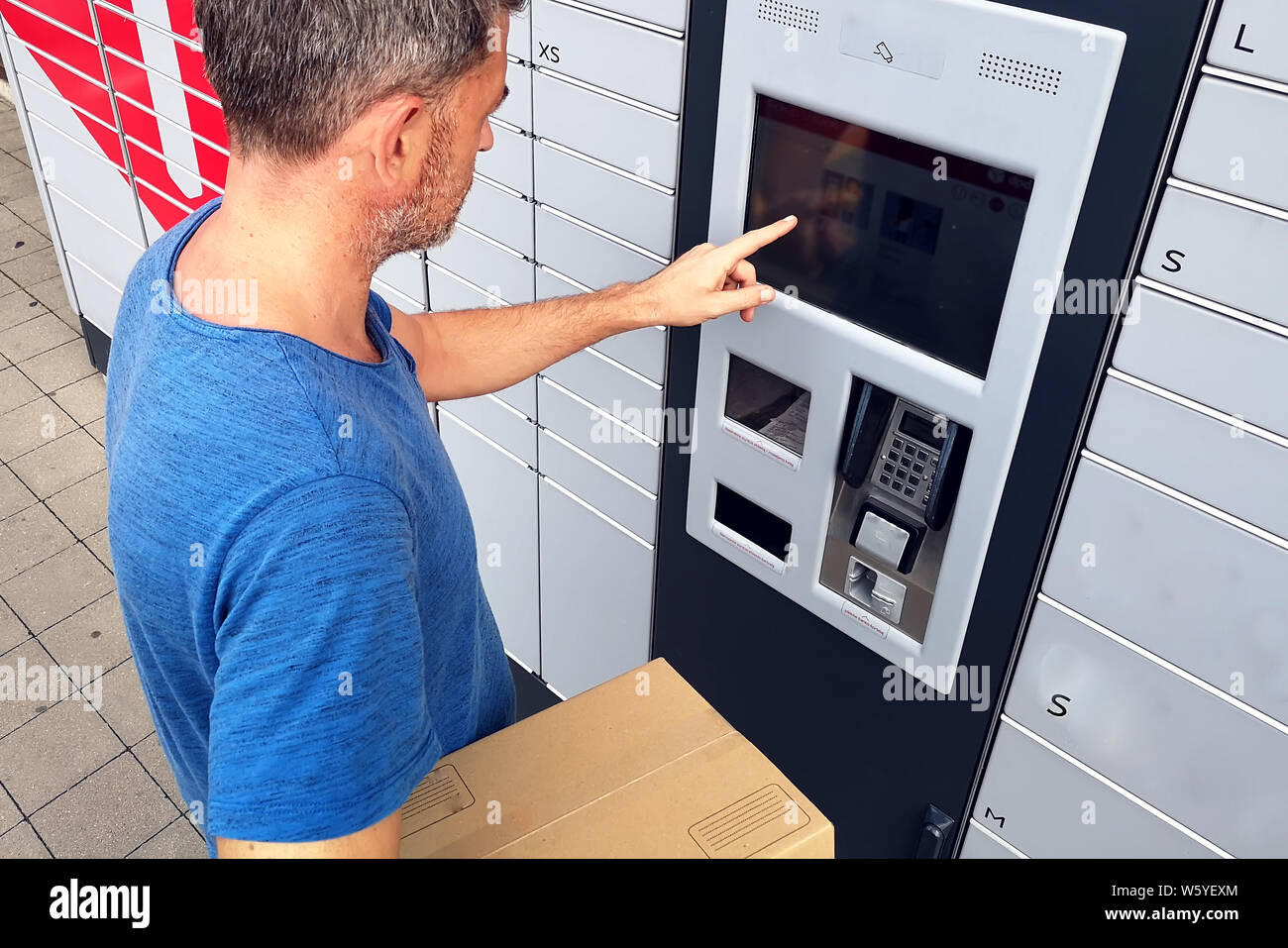 Man-Client mithilfe von automatisierten Self Service post Terminal Machine oder Schrank das Paket für die Lagerung zu hinterlegen. Stockfoto