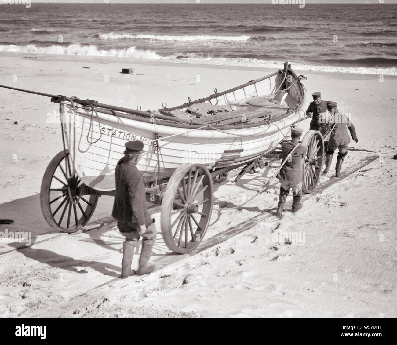 1910s 1920s UNITED STATES COAST GUARD MÄNNER BEWEGTEN LEBEN RETTEN OAR-DRIVEN SURF BOOT ÜBER STRAND SAND AUF RÄDERN BEFÖRDERUNG NJ USA - c 121 HAR 001 HARS BERUF SICHERHEIT TEAMARBEIT LIFESTYLE MEER GESCHWINDIGKEIT GESCHICHTE PASSAGIERE JOBS LÄNDLICHEN VEREINIGTEN STAATEN KOPIEREN RAUM VOLLER LÄNGE KÖRPERLICHE FITNESS PERSONEN, DIE VEREINIGTEN STAATEN VON AMERIKA MÄNNER RISIKO BERUF RÄDER VERTRAUEN TRANSPORT B&W STRAFVERFOLGUNG NORDAMERIKA NORDAMERIKA WEITWINKEL SKILL DISASTER BERUF FÄHIGKEITEN ABENTEUER SCHUTZ STÄRKE STRATEGIE MUT KARRIERE AUFREGUNG MÄCHTIG STOLZ AUF NJ BERUFE MATROSEN UNIFORMEN KONZEPTIONELLE 1790 1848 Stockfoto