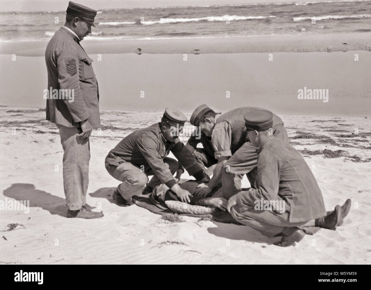 1910s 1920s UNITED STATES COAST GUARD PETTY OFFICER UHREN BESATZUNG VON VIER RENDERING ERSTE HILFE ZUM FÜNFTEN GEBRECHLICHE MANN AM STRAND NJ USA - c 106 HAR 001 HARS LIFESTYLE MEER GESCHICHTE verletzte Passagiere ländlichen Krankheit 6 UNITED STATES KOPIE RAUM FREUNDSCHAFT IN VOLLER LÄNGE KÖRPERLICHE FITNESS PERSONEN, DIE VEREINIGTEN STAATEN VON AMERIKA FÜRSORGLICHE MÄNNER RISIKO SECHS UNPÄSSLICHKEIT VERTRAUEN B&W 5. STRAFVERFOLGUNG NORDAMERIKA NORTH AMERICAN DISASTER LEIDEN UHREN STÄRKE MUT WISSEN FÜHRUNG FORTSCHRITTE STOLZ AUF DIE AUTORITÄT NJ BERUFE MATROSEN UNIFORMEN KONZEPTIONELLE 1790 1848 stilvolle BETREUUNG UNTERSTÜTZUNG SCHIFFBRUCH Stockfoto