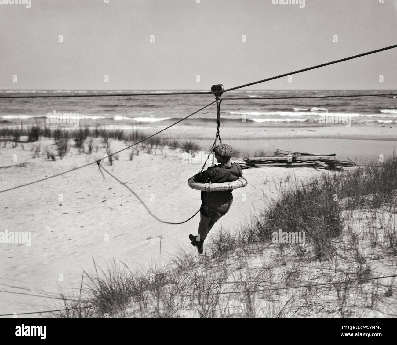 1910s 1920s MANN MITGLIED DER UNITED STATES COAST GUARD REITEN IN LATZHOSEN BOJE BEIM ÜBEN DIE RETTUNG VON MENSCHEN AUS ZERRÜTTETEN SCHIFFE - c 95 HAR 001 HARS KOPIE RAUM PERSONEN, DIE VEREINIGTEN STAATEN VON AMERIKA MÄNNER RISIKO SCHIFFE B&W STRAFVERFOLGUNG NORDAMERIKA AUGENKONTAKT NORDAMERIKANISCHEN ERFOLG SKILL BERUF FÄHIGKEITEN ABENTEUER SCHUTZ STÄRKE MUT AUFREGUNG INNOVATION IN DER NJ BERUFE MATROSEN UNIFORMEN RETTUNG RUINIERTE KONZEPTIONELLE 1790 1848 ESCAPE LONG BEACH ISLAND SUPPORT NEW JERSEY SANDDÜNEN SCHIFFBRUCH REGIERUNGSBEHÖRDE SEEMÄNNER GEBILDET LIFESAVING MITGLIED Mitte - Mitte - erwachsenen Mann MISSION SEASHORE Stockfoto