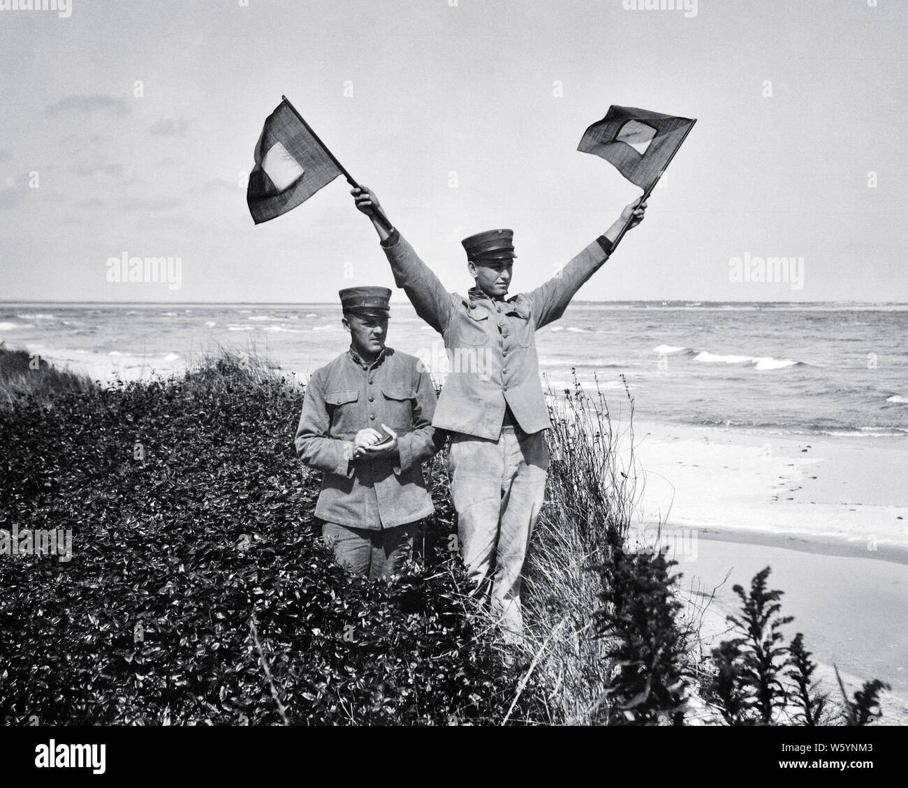 1910 s zwei UNIFORMIERTE MÄNNER IN UNITED STATES COAST GUARD SEMAPHORE SIGNALISIERUNG BUCHSTABEN J LONG BEACH ISLAND NEW JERSEY USA - c 99 HAR 001 HARS MÄNNER RISIKO SURF VERTRAUEN B&W STRAFVERFOLGUNG NORDAMERIKA NORDAMERIKA ERFOLG DISASTER ABENTEUER SCHUTZ STÄRKE MUT BEGEISTERUNG FÜHRUNG mächtig stolz auf Autorität berufen MATROSEN UNIFORMEN SIGNALISIERUNG KONZEPTIONELLE 1790 1848 DUNE ESCAPE LONG BEACH ISLAND STILVOLLE SUPPORT NEW JERSEY SCHIFFBRUCH UNIFORMIERTEN REGIERUNGSBEHÖRDE SEEMÄNNER SEMAPHORE GEBILDET LIFESAVING Mitte - Mitte - erwachsenen Mann MISSION PRÄZISION SEASHORE EINZIGARTIGE 1915 SCHWARZ UND WEISS Stockfoto